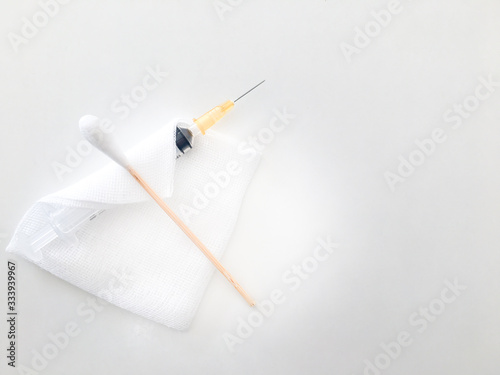 cotton bud or swab on gauze and syringe on white background for medical treament  concept with copy space photo