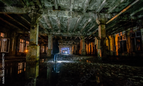 Interior of an old abandoned soviet building with cracked ragged walls and leaking roof and wet floor at night with flashlights of stalkers