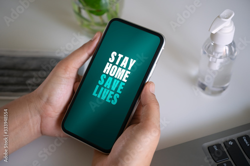 Stay home save lives for self quarine times. Hand holding mobile smart phone. Coronavirus or Covid-19  social media campaign concept, stay at home, social distancing for protect corona virus concept. photo