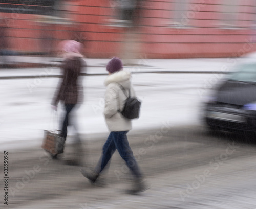Busy city people on zebra crossing in motion blur. Winter snowy day, dangerous situation