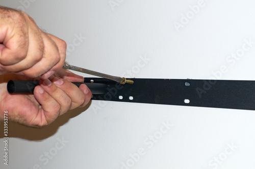 Φωτογραφία Men's hands screwing a shelf holder with a screwdriver on a wall - close-up