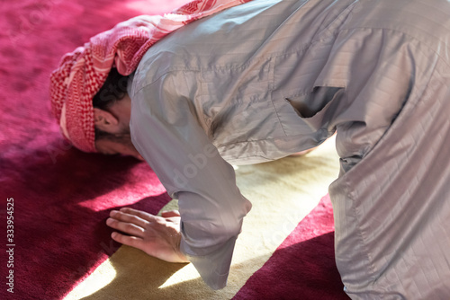 Young Arabic Muslim man  praying. Doing a dailly pray inside modern beautiful mosque. photo