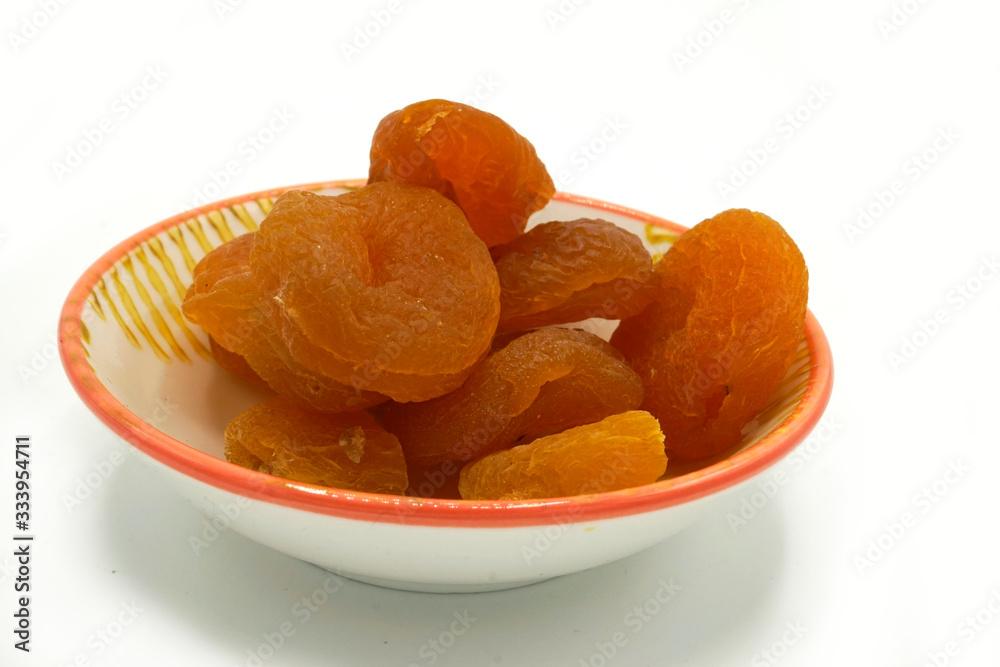 Dried apricots on a ceramic saucer isolated on white background. Energy and fiber natural source. Dieting food. Dried apricots on a ceramic saucer isolated on white background. Energy and fiber natural source. Dieting food.