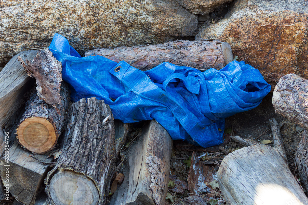 Blue Tarp on an Outdoor Wood Pile with Rock Wall in Background Stock Photo Adobe Stock
