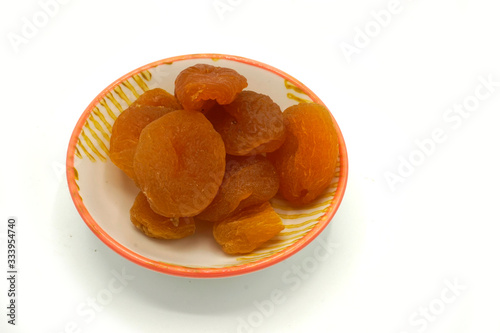 Dried apricots on a ceramic saucer isolated on white background. Energy and fiber natural source. Dieting food. photo