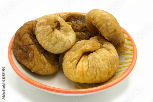 Dried figs on a ceramic saucer isolated on white background. Energy and fiber natural source. Dieting food. photo