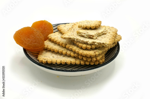 Dried fruits and digestive biscuits on a ceramic saucer isolated on white background. Energy and fiber natural source. Dieting food. photo