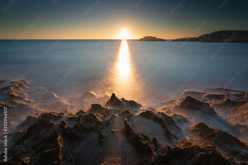 sunset over the sea with rocks in the foreground