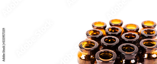 Many empty brown glass medical bottles isolated on a white background. The course of treatment is completed. Mass vaccination. Capacities for tablets. Production of containers.