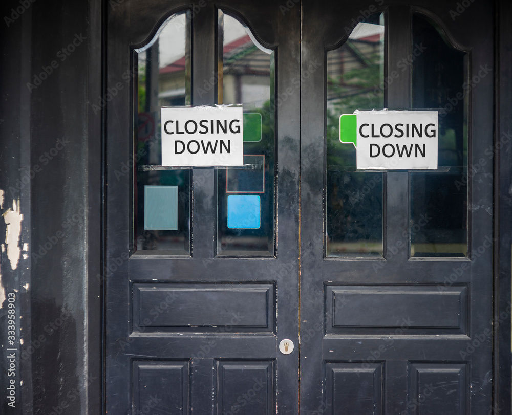 Closing Down sign painted on the window of a dress shop.