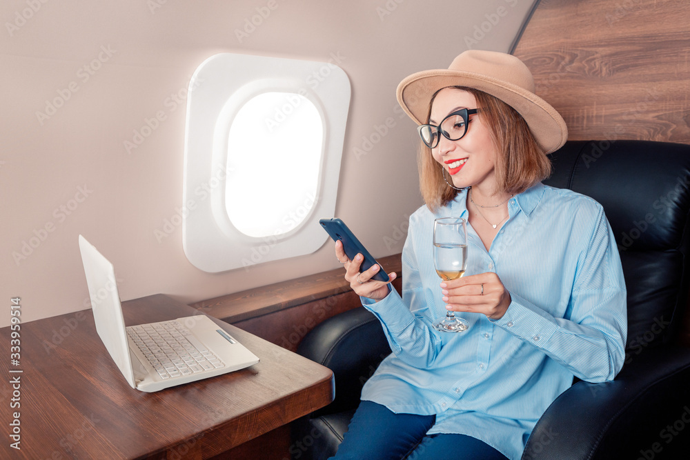 Φωτογραφία An Asian businesswoman flies in business class on a corporate plane and works with a laptop and smartphone