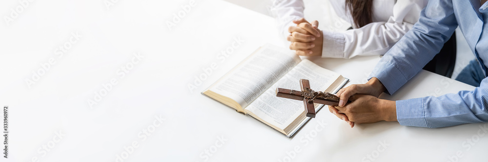 Obraz premium Christian woman praying with hands together on holy bible and wooden cross. Woman pray for god blessing to wishing have a better life and believe in goodness.