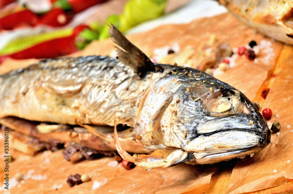 Smoked mackerel with garlic, pepper and coarse salt on baking paper. Smoked mackerel with garlic, pepper and coarse salt on baking paper.