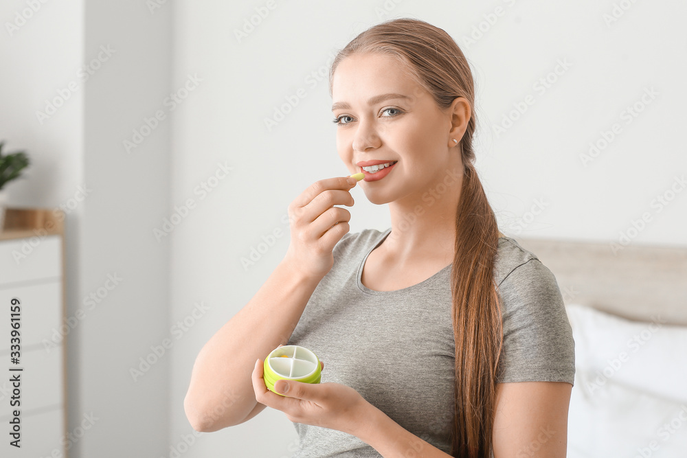 Young woman taking pill at home