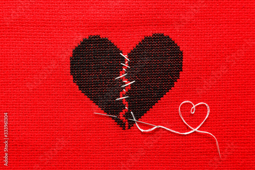 Black broken heart on red background. Embroidery.