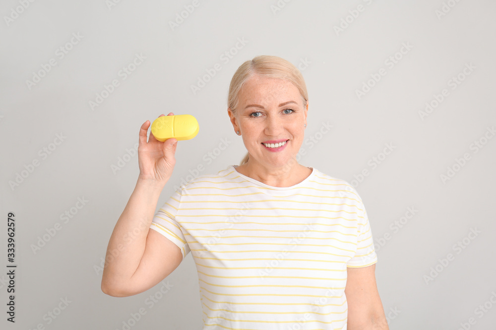 Mature woman with pills box on light background Mature woman with pills box on light background