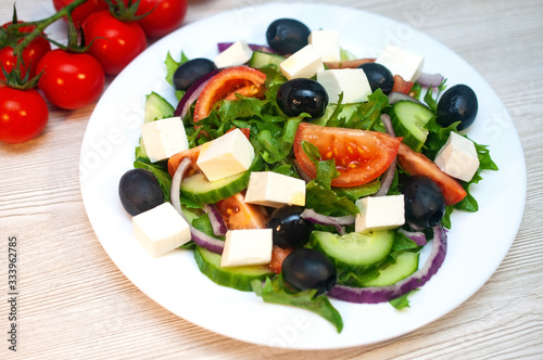 Greek salad with tomatoes, cucumbers and feta cheese with olives on the table