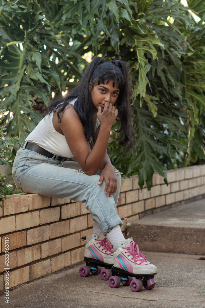 Naklejka premium Young lady with roller skates sitting outside