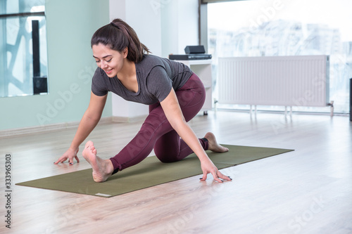 Photo of young woman practicing yoga indoor. Beautiful girl practice yoga in class. Yoga studio instructor. Blurred background.