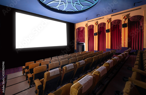 Cinema theater screen in front of seat rows in movie theater showing white screen projected from cinematograph. The cinema theater is decorated in classical style for luxury feeling of movie watching. photo