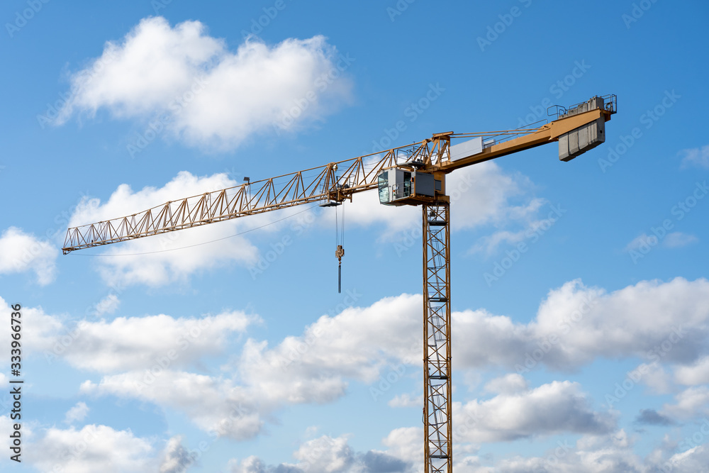 yellow construction crane and cloudscape on a construction site in berlin, as background for a website with free space for text