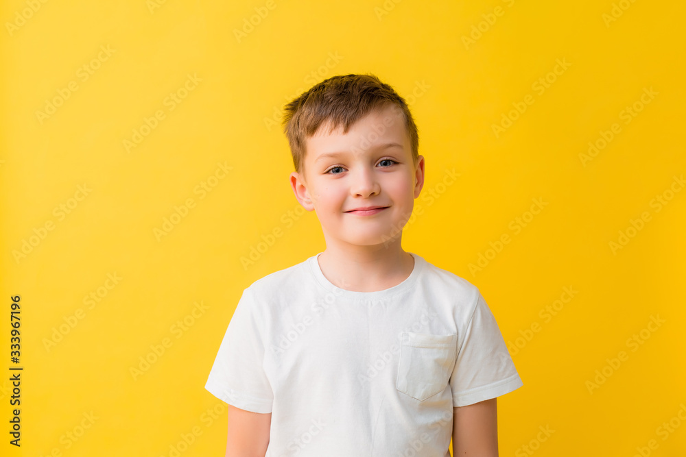 Happy baby boy of 7 years in a white T-shirt on a yellow background Happy baby boy of 7 years in a white T-shirt on a yellow background