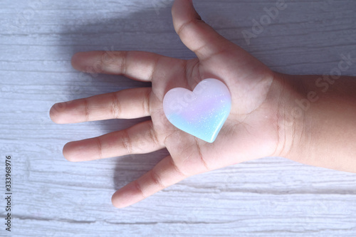 Baby's hands hold a small heart on a white background