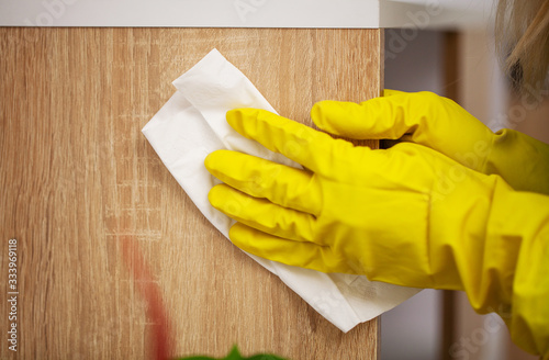 Close up of worker hand wiping dust in office in yellow gloves