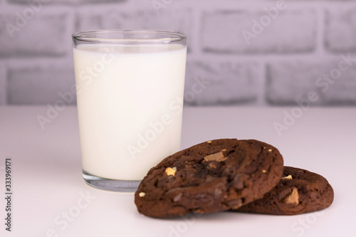  Milk in a glass and chocolate homemade cookies on a white background. Concept for a delicious snack.