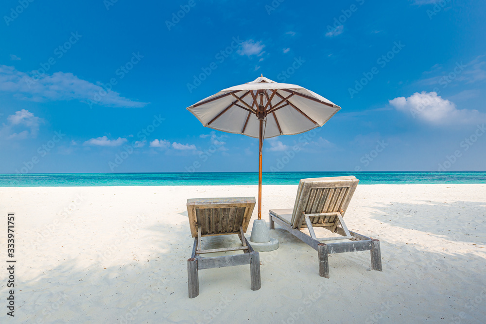 Island beach with loungers and umbrella on white sand close to blue sea. Idyllic summer travel and vacation landscape