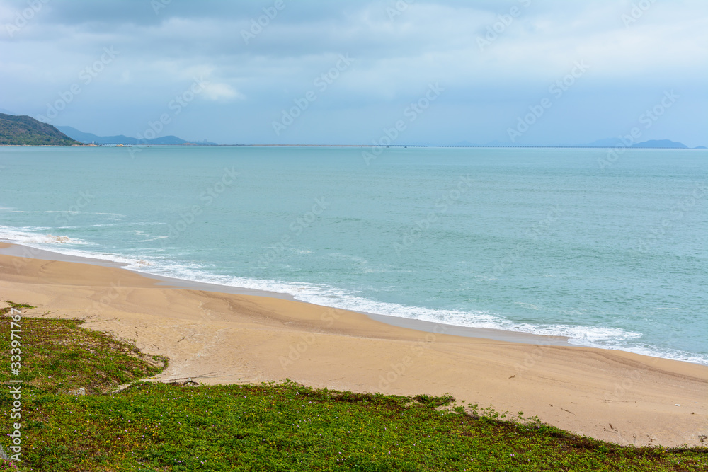 Cloudy day, sand deserted beach of the coast in South China Sea. Sanya, island Hainan, China. Nature Landscape.