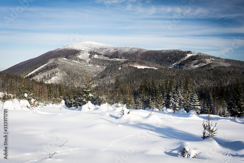Winter scenery with Smrk mountain, plenty of snow, forest, hills and blue sky with few clouds on the way to Martinak in Beskydy mountains