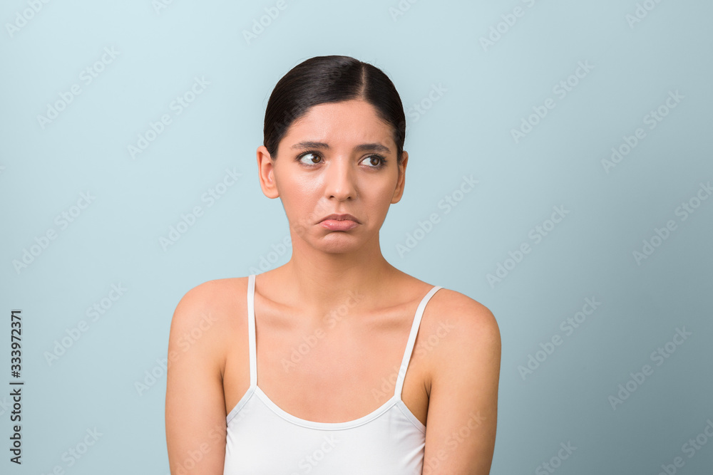 very sad depressed woman in isolation about to cry looking away against grey background very sad depressed woman in isolation about to cry looking away against grey background