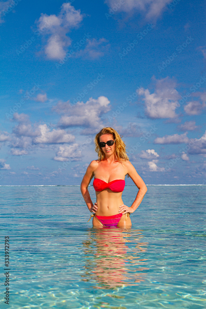 Beautiful young woman in sexy bikini standing at sea beach enjoying summer weather, sunny day, blonde woman, bikini, sunglasses