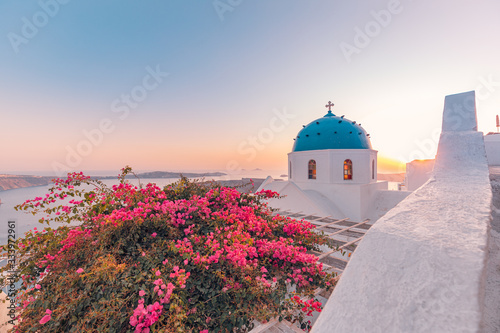 Amazing travel landscape. Beautiful sunset on Santorini island, Greece.. Romantic summer vacation or couples holiday banner. Flowers under sunset sky, church and beautiful white architecture, sea view