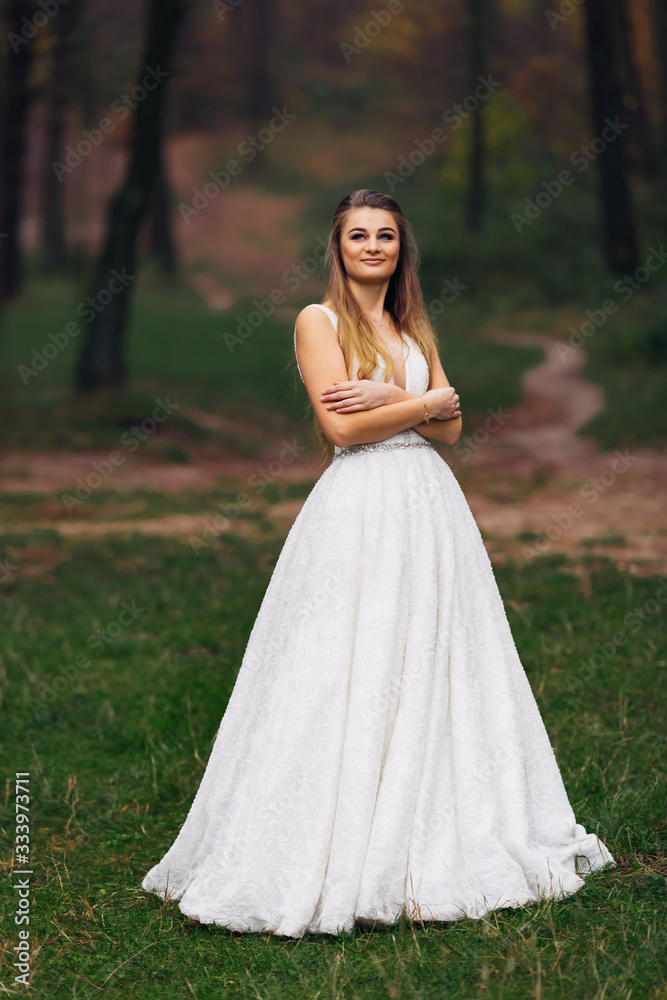 bride in wedding dress crossed her arms and smiles. walk in the
