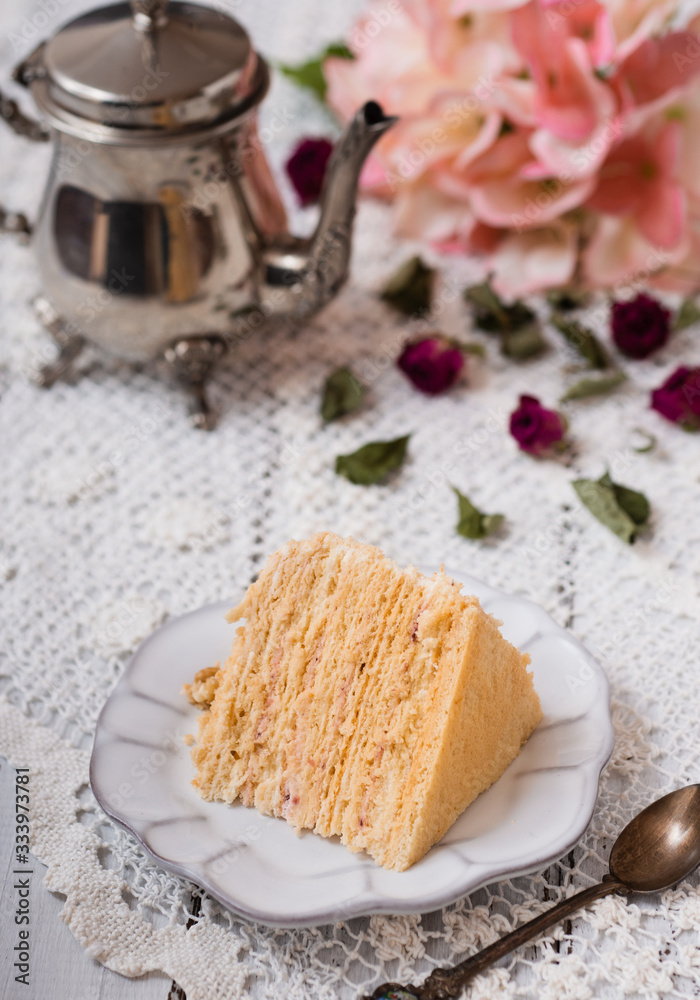 Sweet homemade layered honey cake on a white plate with coffee.