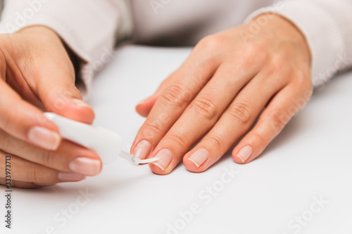 close up woman varnishing nails at home. self nail strengthening while in quarantine