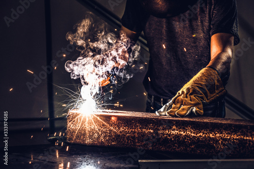 Φωτογραφία Metal welder working with arc welding machine to weld steel at factory while wearing safety equipment