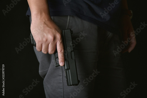 Man holding gun close to the body, Killer with 9mm handgun pistol waiting for robbing the victim, Weapon and violence crime concept.A