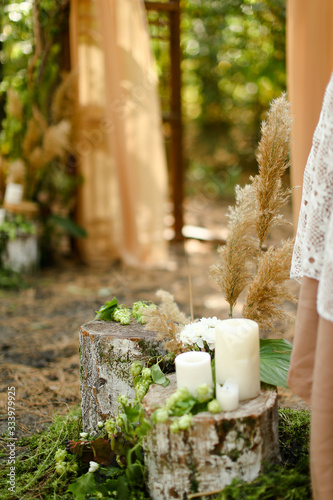 White paraffin candles on wood stumps near wedding altar. photo