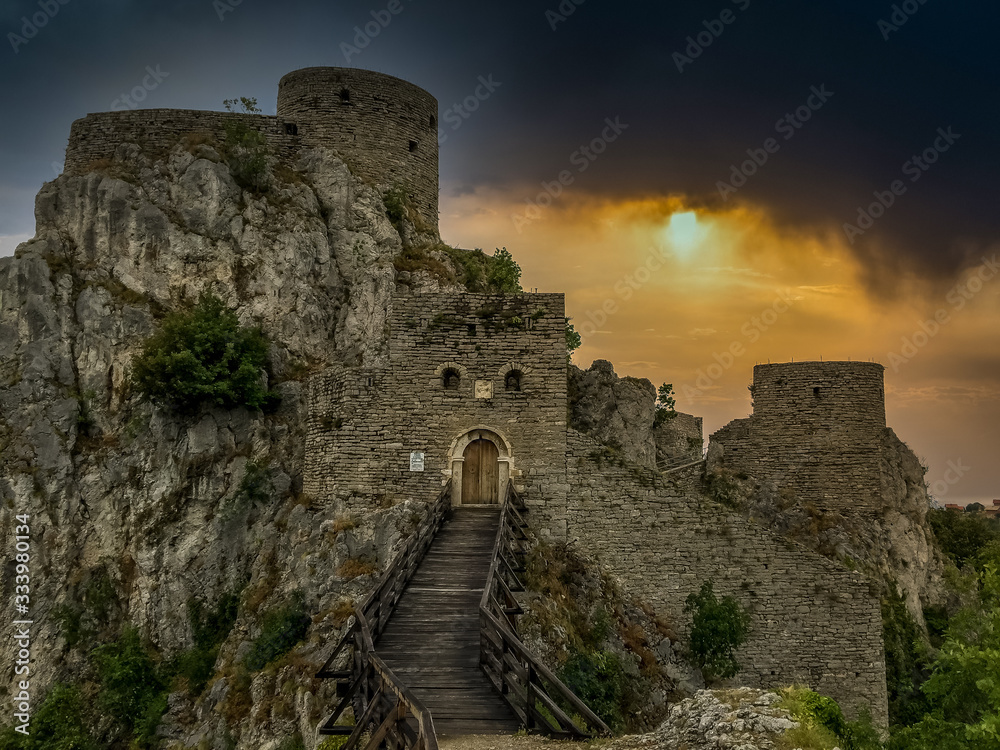 Sunset view of partially restored ancient Ottoman fortress Srebrenik castle with gate tower, wooden bridge over the moat round tower in Bosnia Herzegovina Serbian Republic