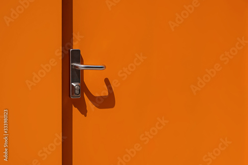 Obraz na plátně Bright orange metal door with handle close-up. Modern exterior