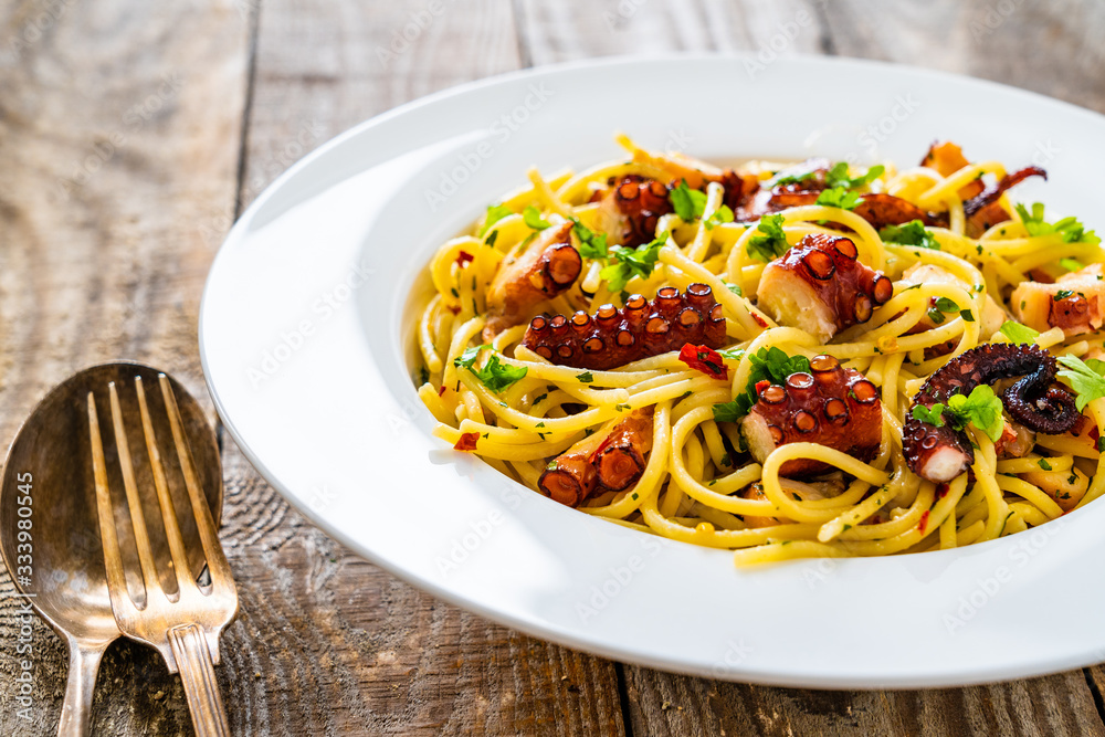 Spaghetti with fried octopus on wooden table Spaghetti with fried octopus on wooden table