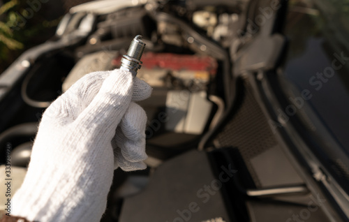 Mechanic hold new iridium spark plug with small electrode for good and high precision spark in difficult condition, high boost or lean air fuel ratio. This image for use to automotive part or service.