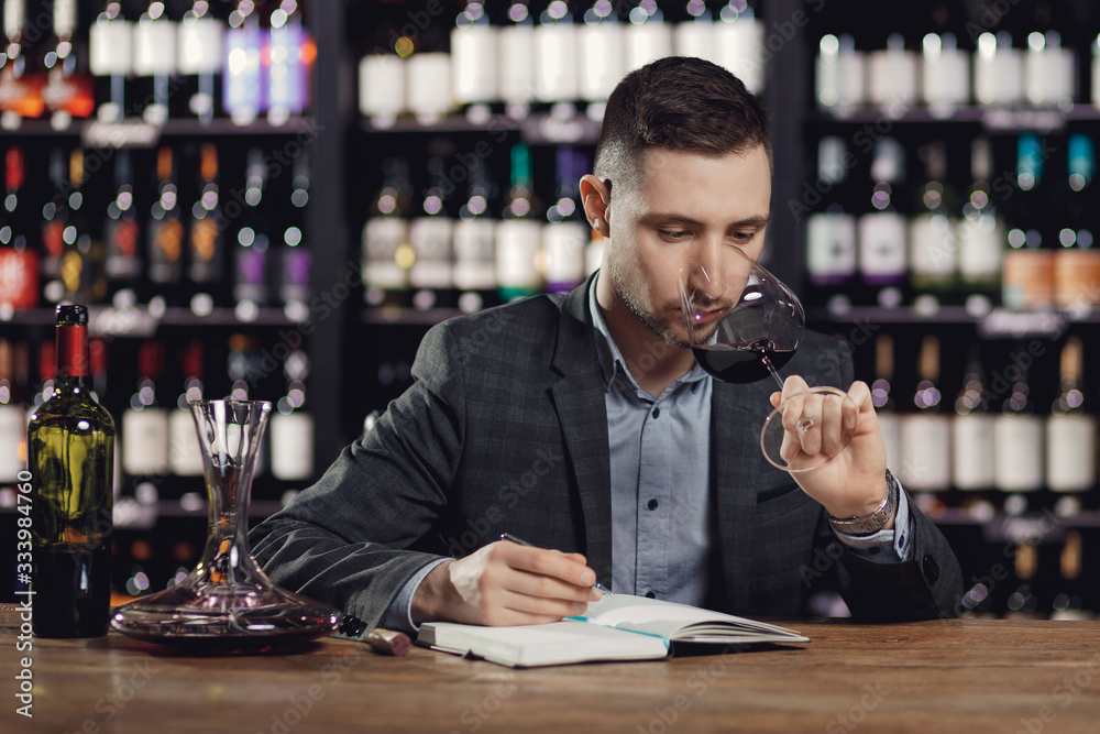 Sommeliers male tasting red wine and making notes aroma degustation card Sommeliers male tasting red wine and making notes aroma degustation card