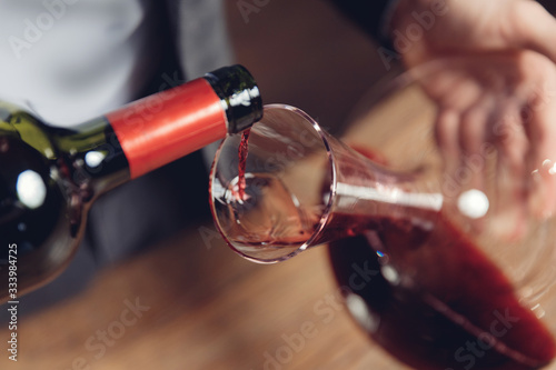 Sommelier man pours red wine into decanter for aeration of taste and aroma photo