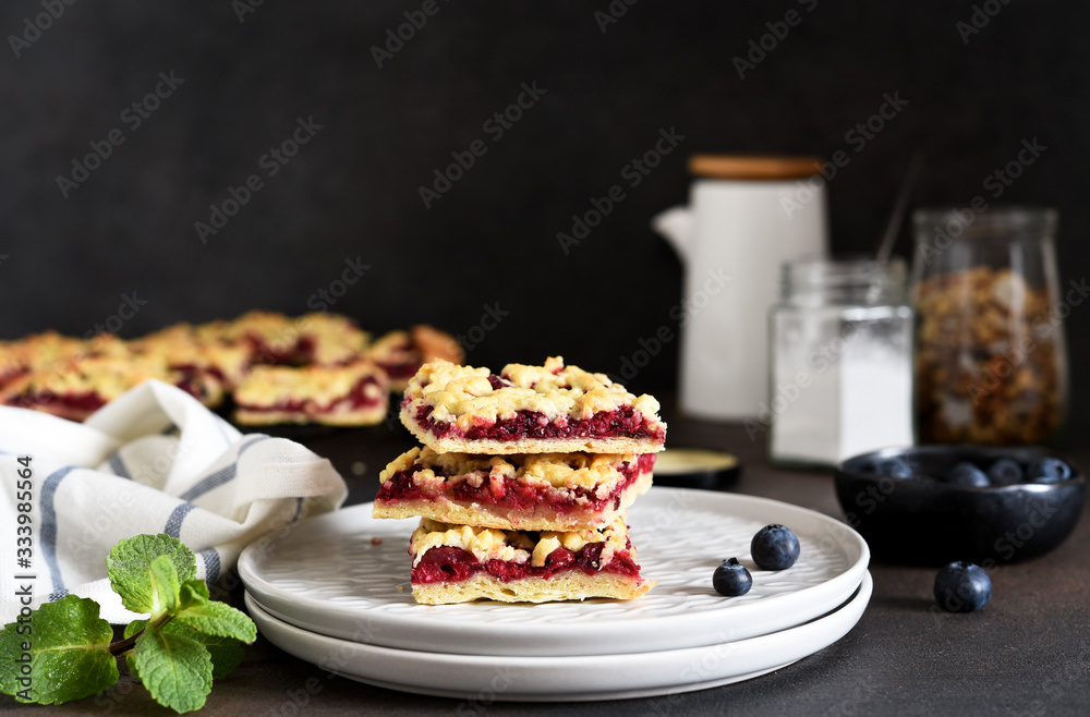 Tasty grated pie with cherries and blueberries on a dark background. Horizontal focus.