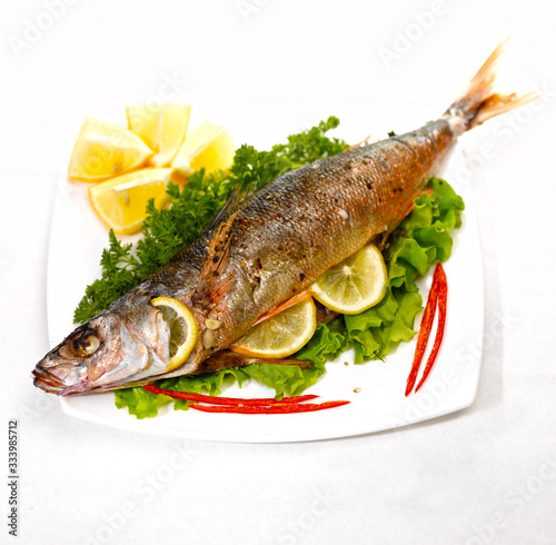 fried fish on a white plate on a kitchen table