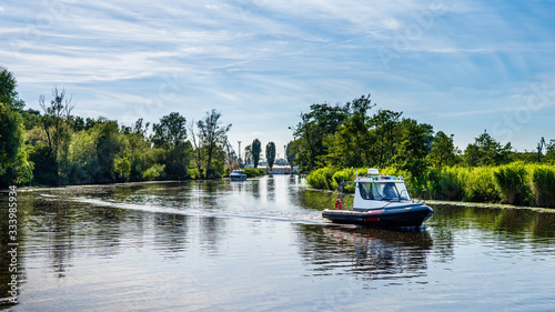 Motor inflatable boat floats on a river  surrounded by river reeds and tries  beautiful summer day on Szczecin yacht marina  Poland